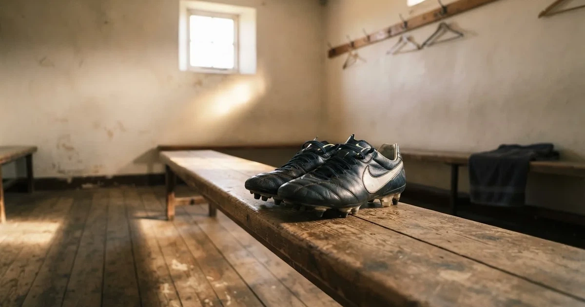 Ein Paar Fussballschuhe steht auf einer Holzbank in einer leeren Umkleide, Morgenlicht fällt durch ein kleines Fenster.