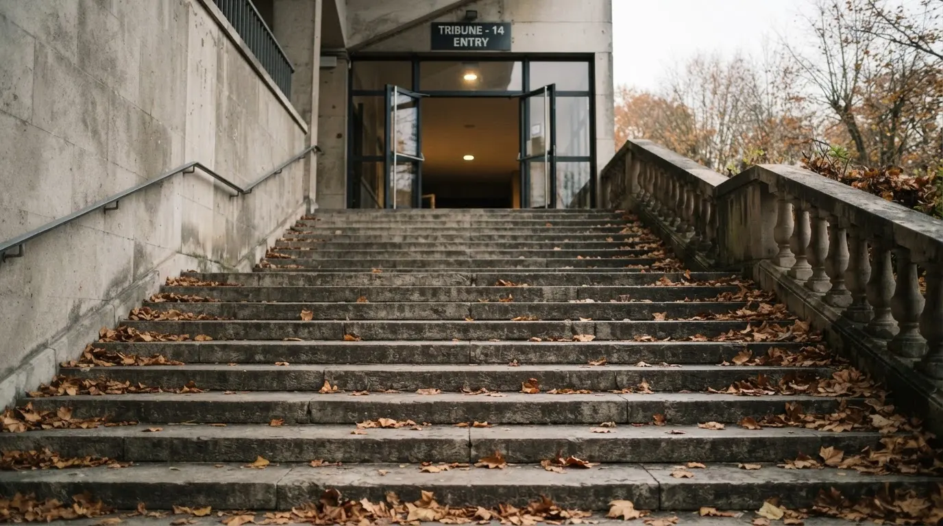 Eine breite Steintreppe führt zum Eingang einer Tribüne, Herbstlaub liegt auf den Stufen.