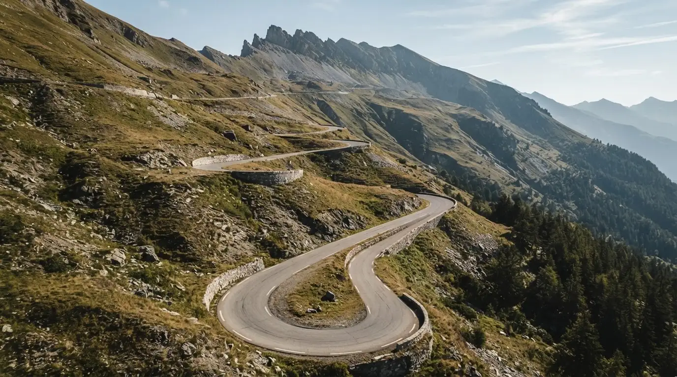 Eine Passstrasse zieht sich in Kehren einen Alpenhang hinauf, kein Fahrzeug ist zu sehen.